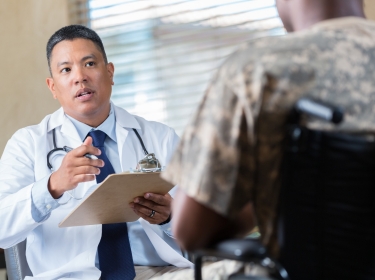 Doctor talks with armed forces veteran during a health evaluation