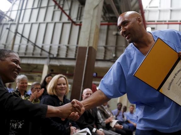 Jerome Boone shakes hands with members of the audience after graduating from a computer coding program at San Quentin State Prison in California, April 20, 2015